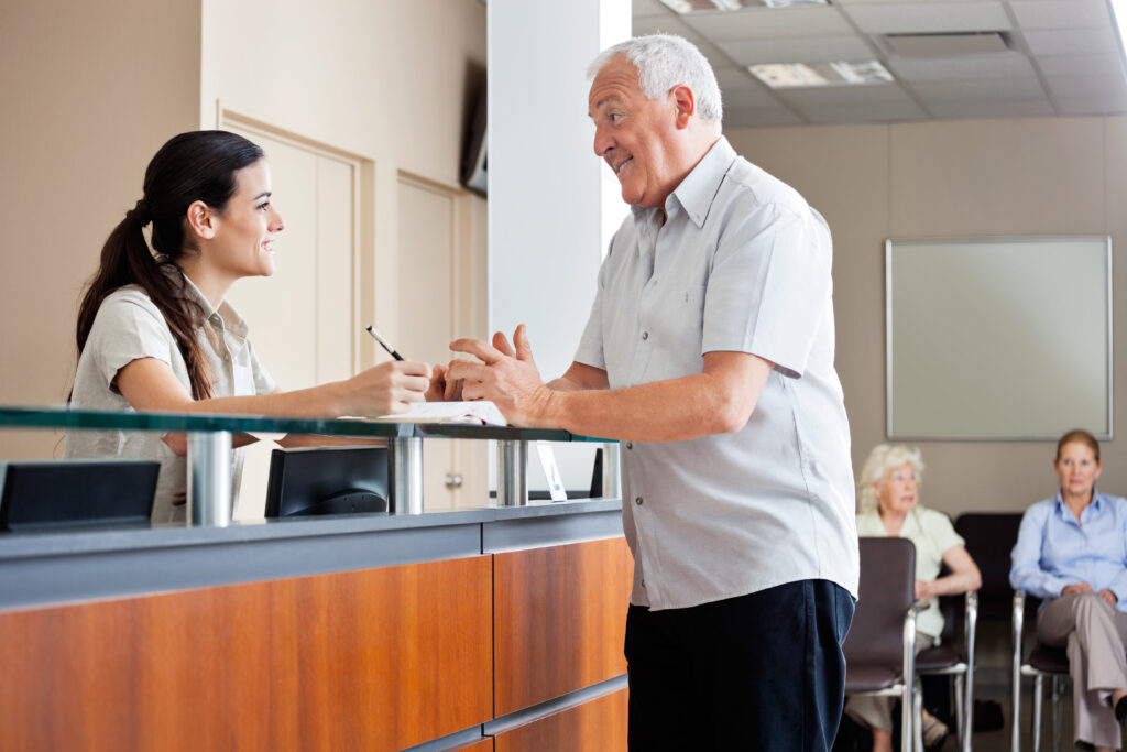 Receptionist talking to a man at a medical practice
