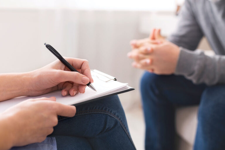 Close up of provider writing on a clipboard across a patient